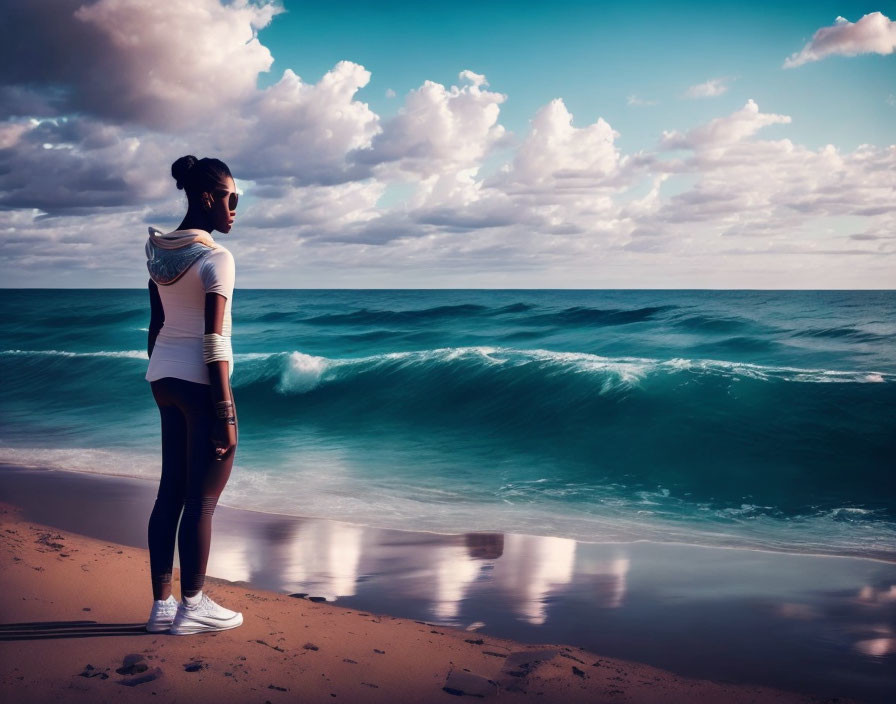 Woman standing on sandy beach gazing at ocean waves at dusk or dawn