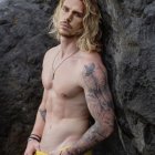 Muscular blond superhero with blue eyes and gold bracelets in icy landscape