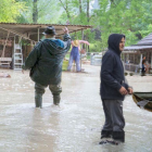 Flooded suburban area with people in rain gear and boats