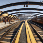 Vintage orange train at ornate station with glass roofs and columns.