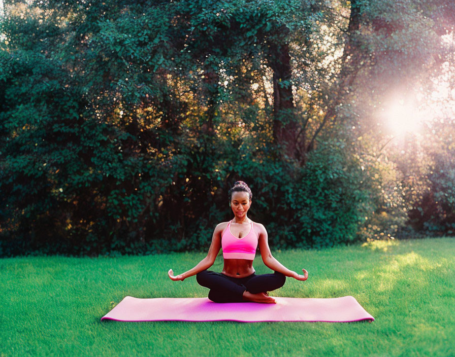 Woman practicing yoga in peaceful park at sunset on magenta mat surrounded by greenery