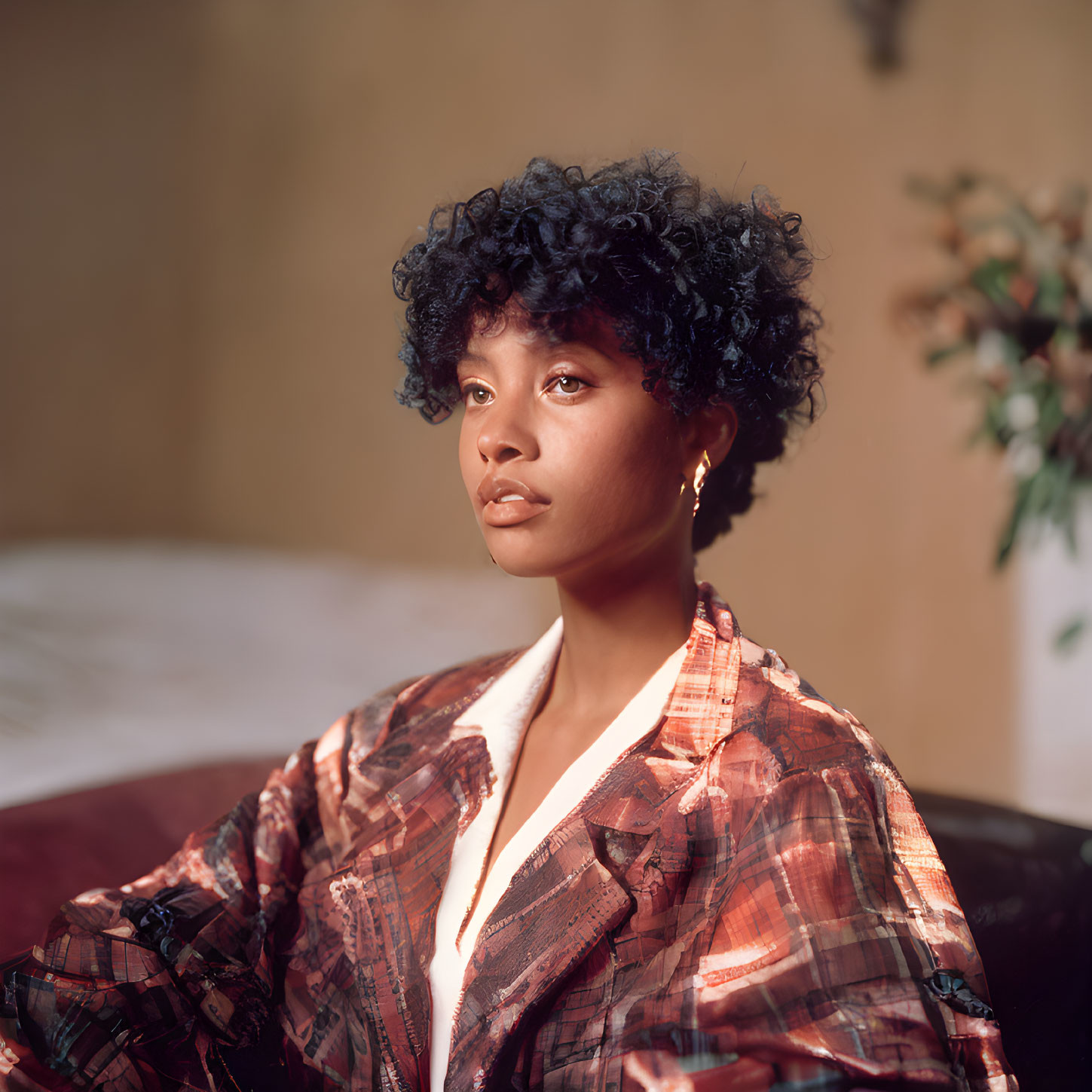 Curly-Haired Woman in Plaid Jacket Contemplates in Softly Lit Room