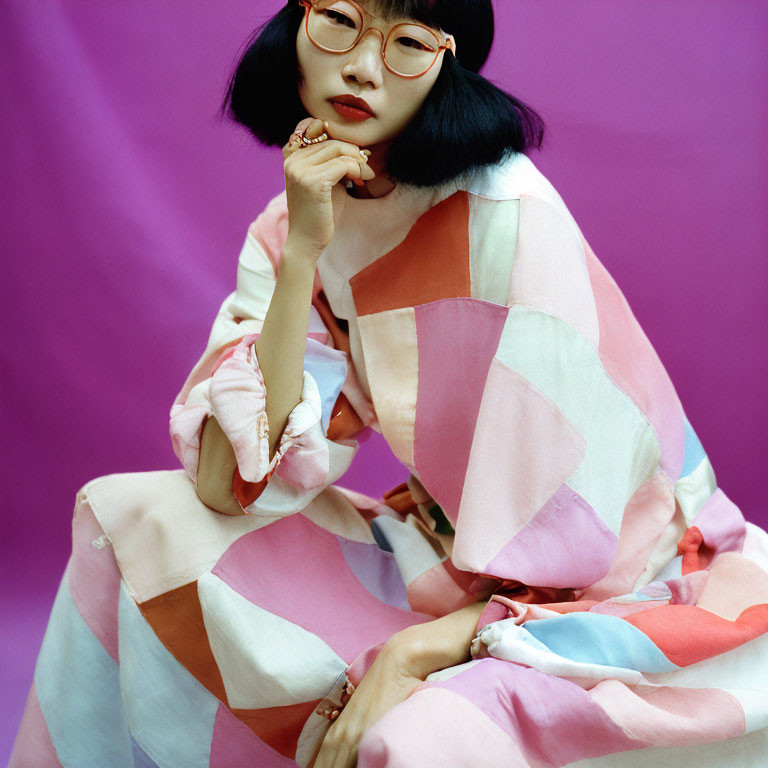 Bobbed hair woman in red glasses poses in pastel outfit on purple background