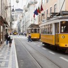 Vintage trams and classical architecture on cobblestone street with pedestrians