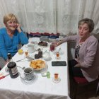 Two women enjoying wine and a meal in an elegantly furnished dining room