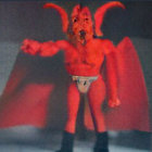 Red devil action figure with horns and wings in smoky backdrop.