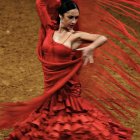 Woman in Luxurious Red Gown and Tiara Poses Against Golden Background