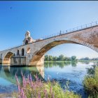 Fantasy bridge with flower decorations over calm river and castle in serene landscape