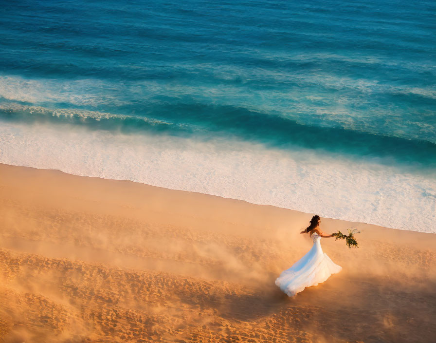 Bride with bouquet on sandy beach at golden hour