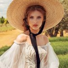 Woman with braid and wide-brimmed hat in sunny, flower-filled landscape