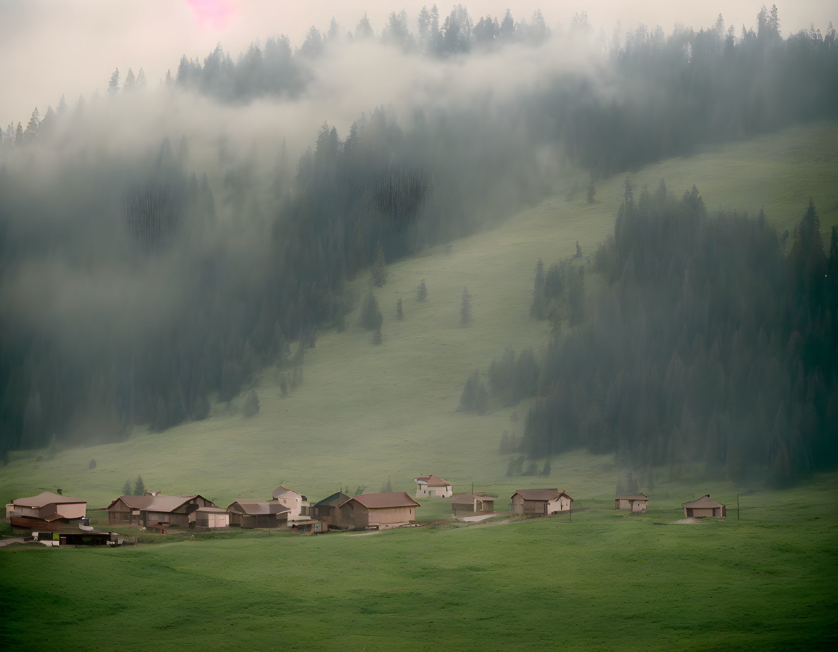 Scenic village nestled in misty valley with pink sky