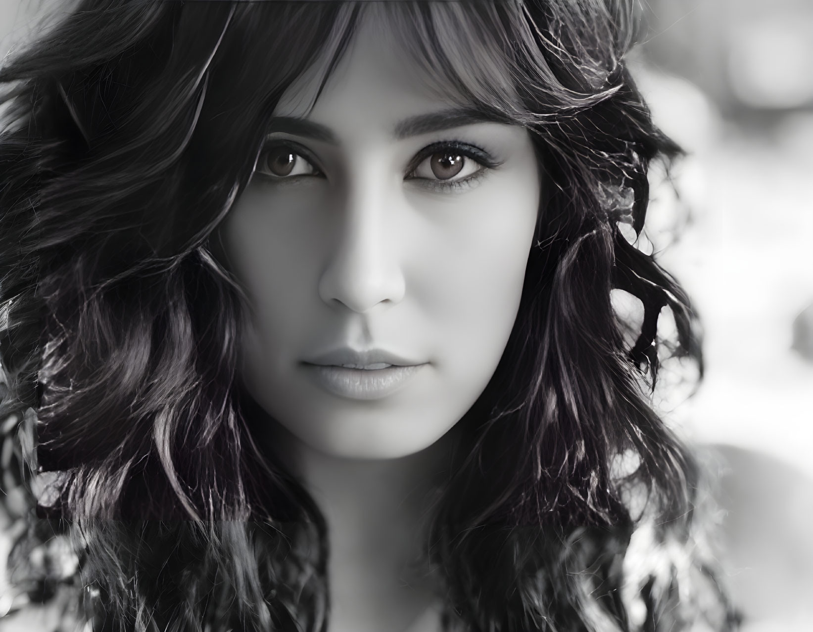 Monochrome portrait of woman with wavy hair and intense gaze