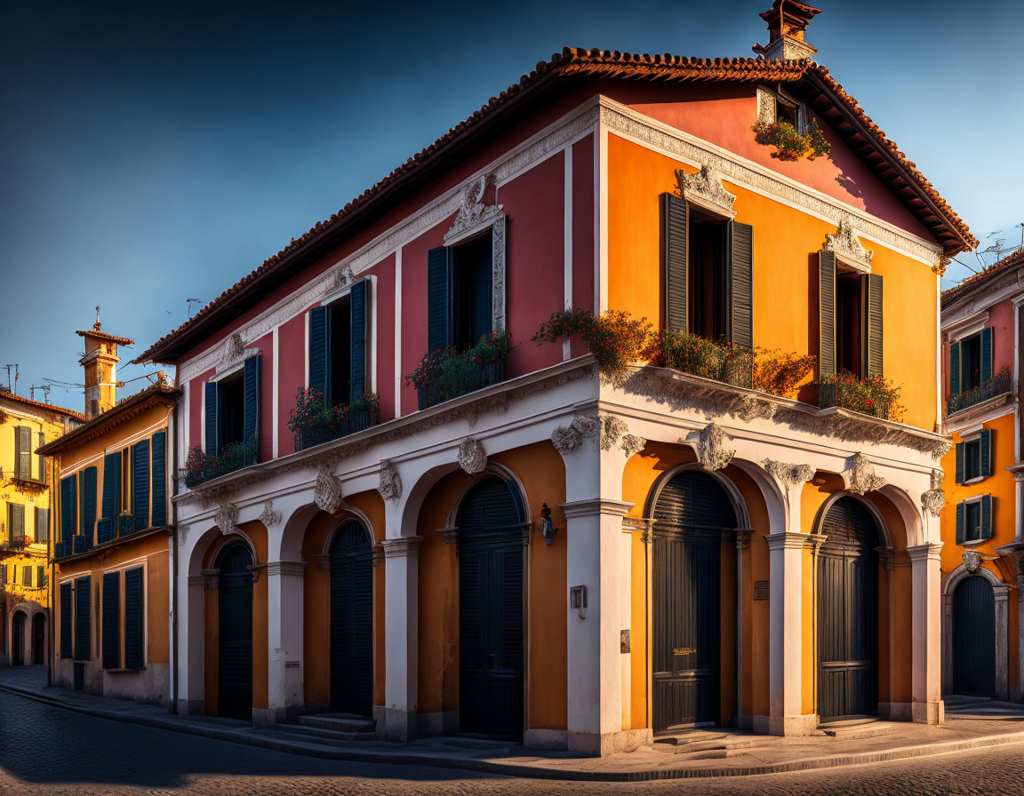 Traditional building with arched doorways and flower boxes in orange and pink hues under warm sunlight.