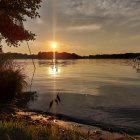 Tranquil sunset painting with sailboats and trees reflecting on water