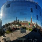 Surreal architecture in giant reflective sphere on blue sky.