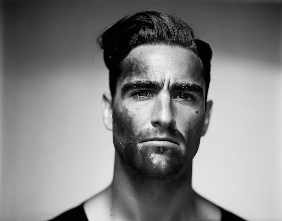 Monochrome portrait of a man with slicked-back hair and strong jawline