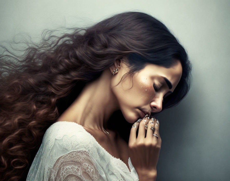 Woman with Long Brown Hair in White Lace and Ornate Rings Poses Pensively