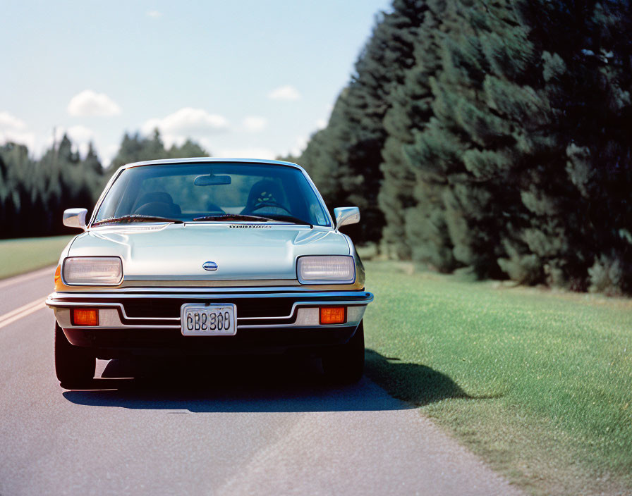 Vintage Sports Car with Pop-Up Headlights Parked on Lush Tree-Lined Road