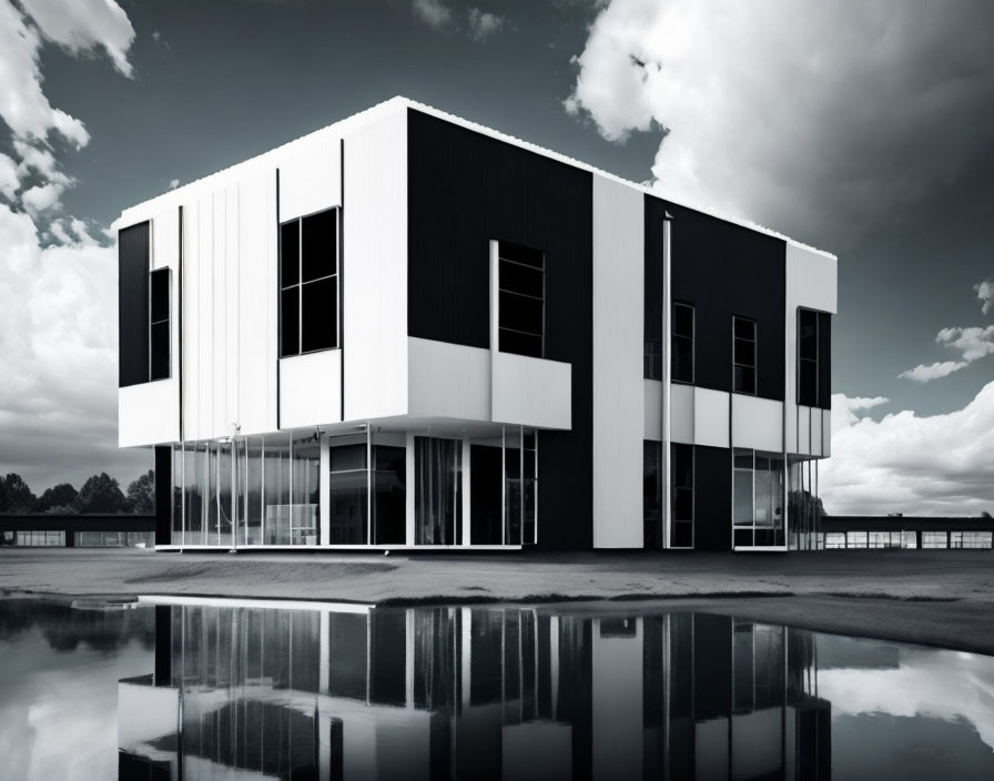 Reflective black and white two-story building under dramatic sky mirrored in water