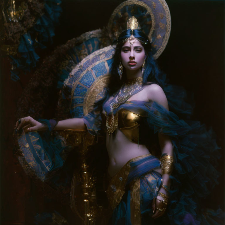 Ornate gold and blue attire woman with elaborate jewelry on dark, moody background