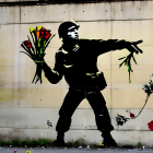 Silhouette of person in militarized outfit with flowers and gun against wall