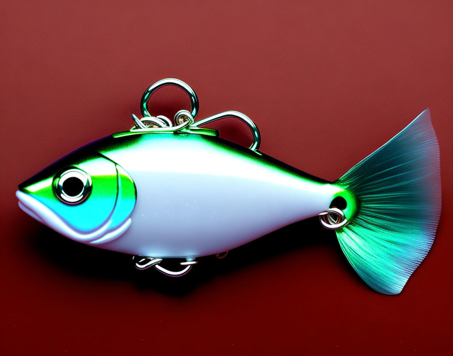 Shiny green and blue-silver fish keychain on red background