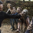 Group of survivors led by bearded man in leather jacket in zombie-infested landscape