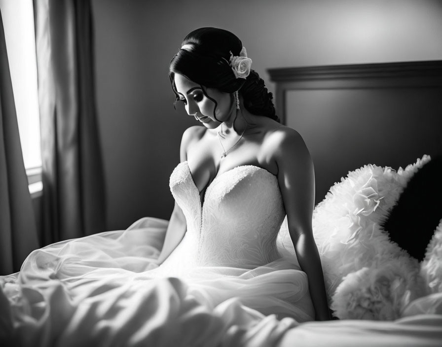 Serene bride in strapless gown by window, light and shadows.