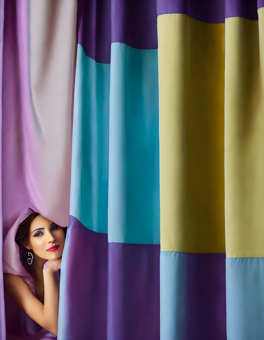 Playful woman behind vibrant multicolored curtains