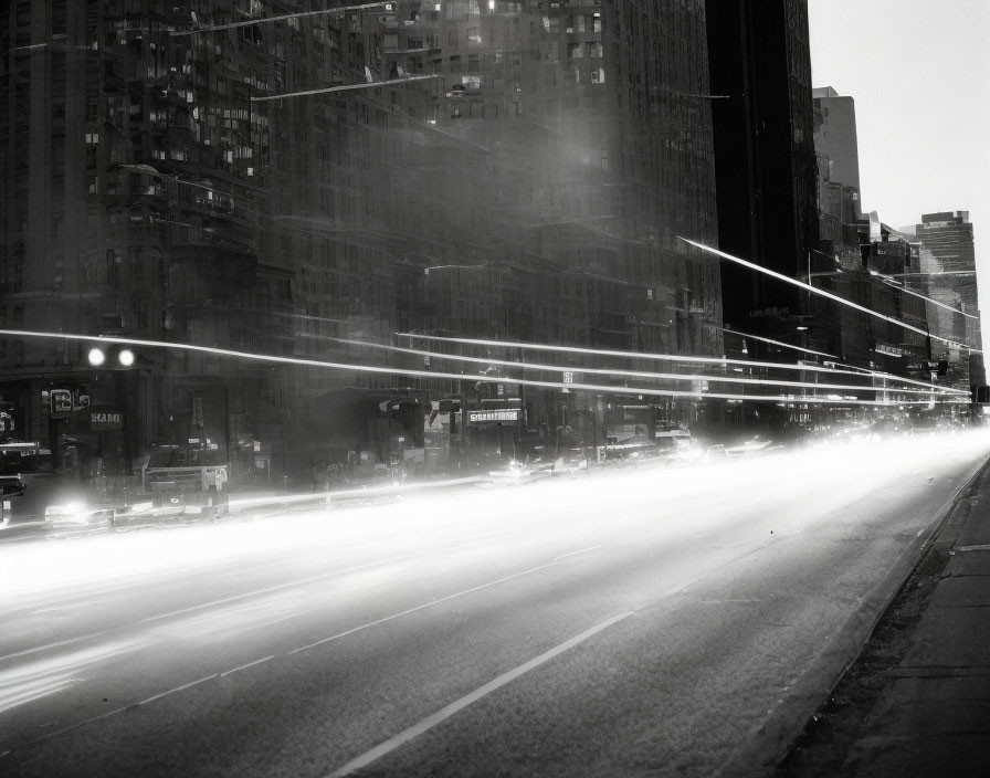 Monochrome cityscape at night with light trails and tall buildings