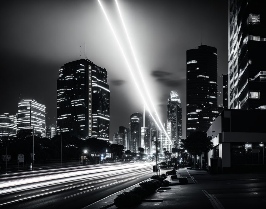 Monochrome cityscape at night with vehicle light trails and illuminated skyscrapers