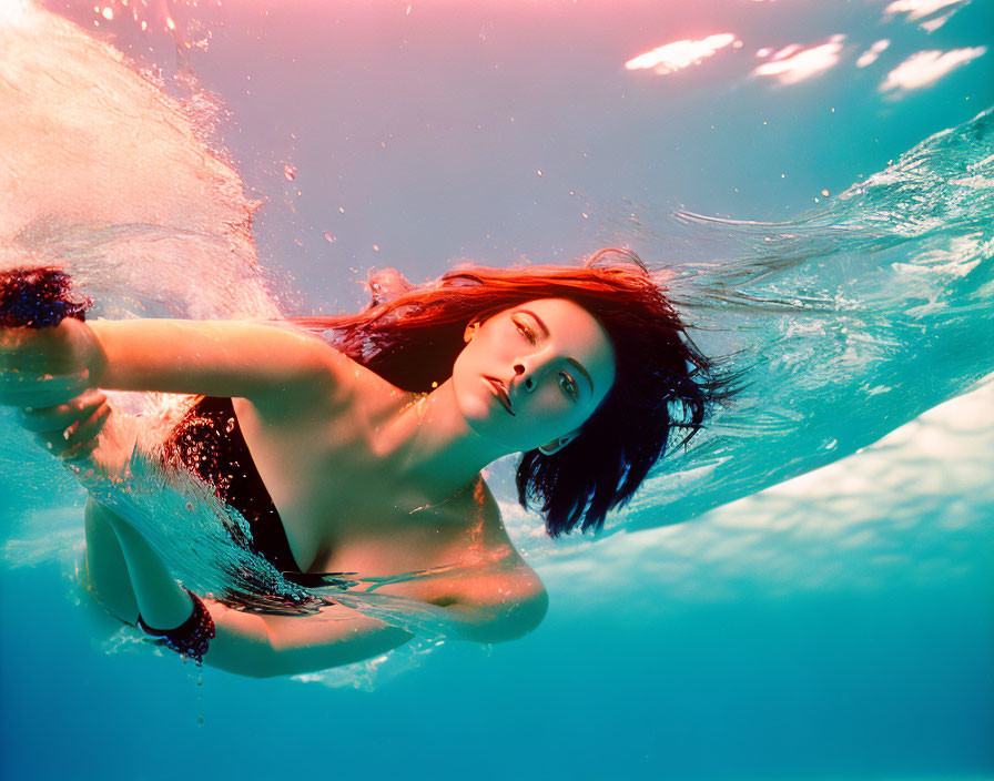 Woman with flowing hair swimming underwater in ethereal scene