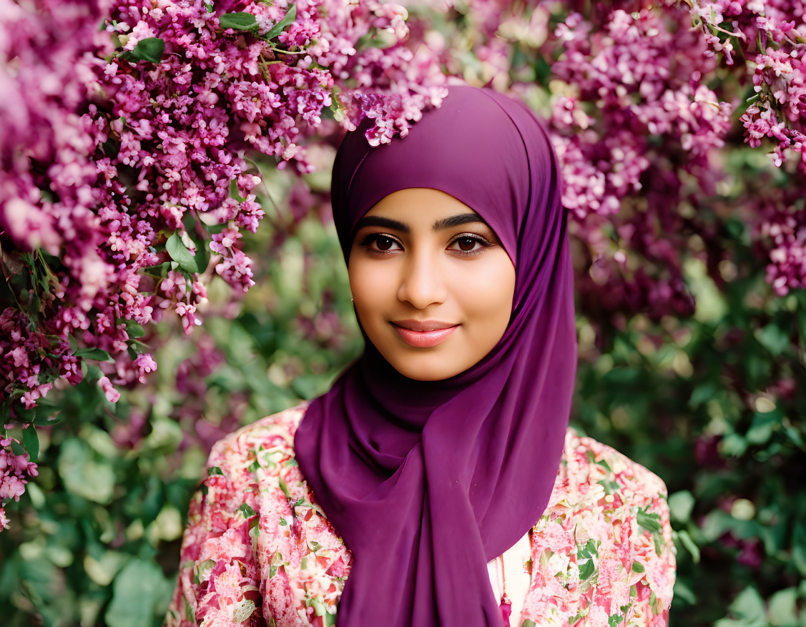 Woman in Purple Hijab Smiling Among Pink Blossoms