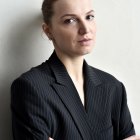 Professional woman in pinstriped suit smiling against beige background