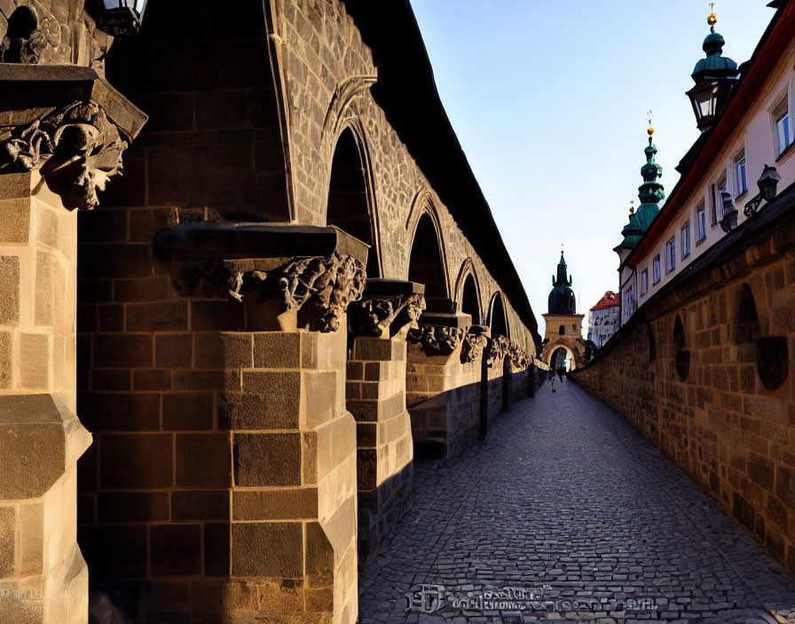 Gothic arches and cobblestoned street leading to green spire at dusk