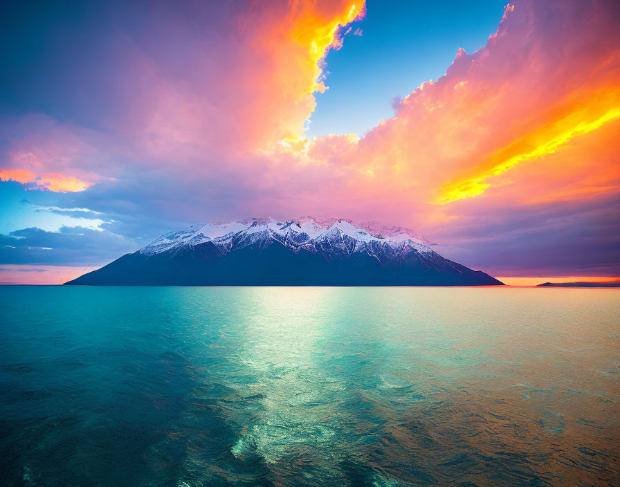 Vivid orange and purple sunset over tranquil sea with snow-capped mountain