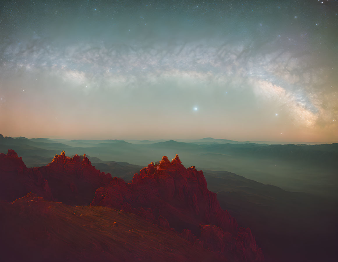 Layered mountains under majestic night sky with prominent galaxy