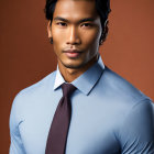 Stylish man in light blue shirt and tie on amber backdrop