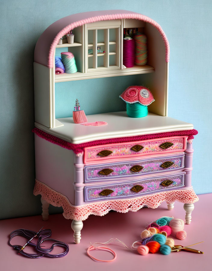 Miniature wooden vanity with pink and white lace detail and brass handles, showcasing sewing accessories.