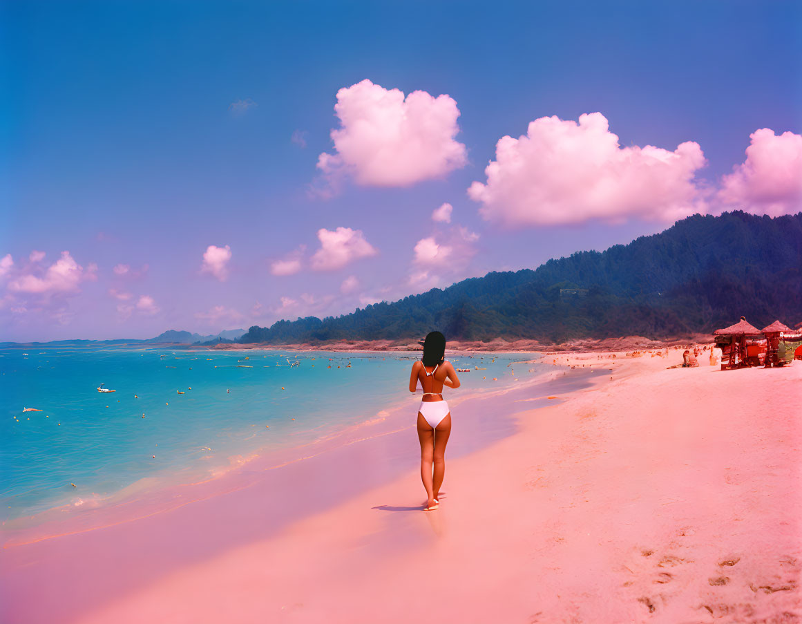 Woman in white bikini strolling on vibrant pink sand beach