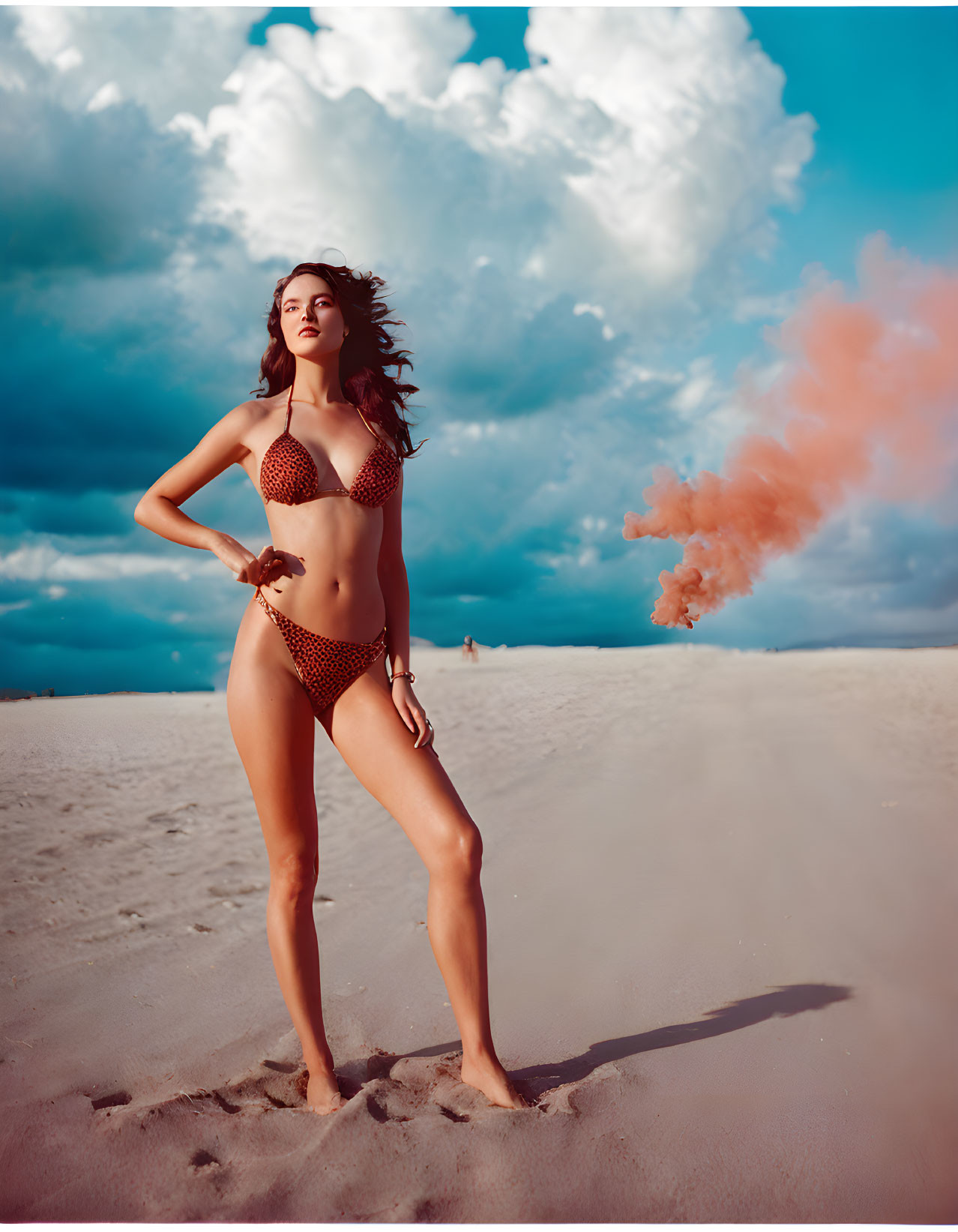 Woman in Polka-Dot Bikini on Beach with Orange Smoke Flare