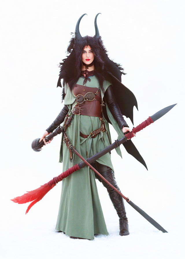 Fantasy-themed costume with horns, green dress, black cape, and staff.