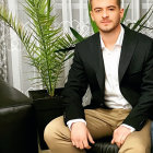 Man in Black Blazer and Khaki Trousers Against Silver Sequin Backdrop