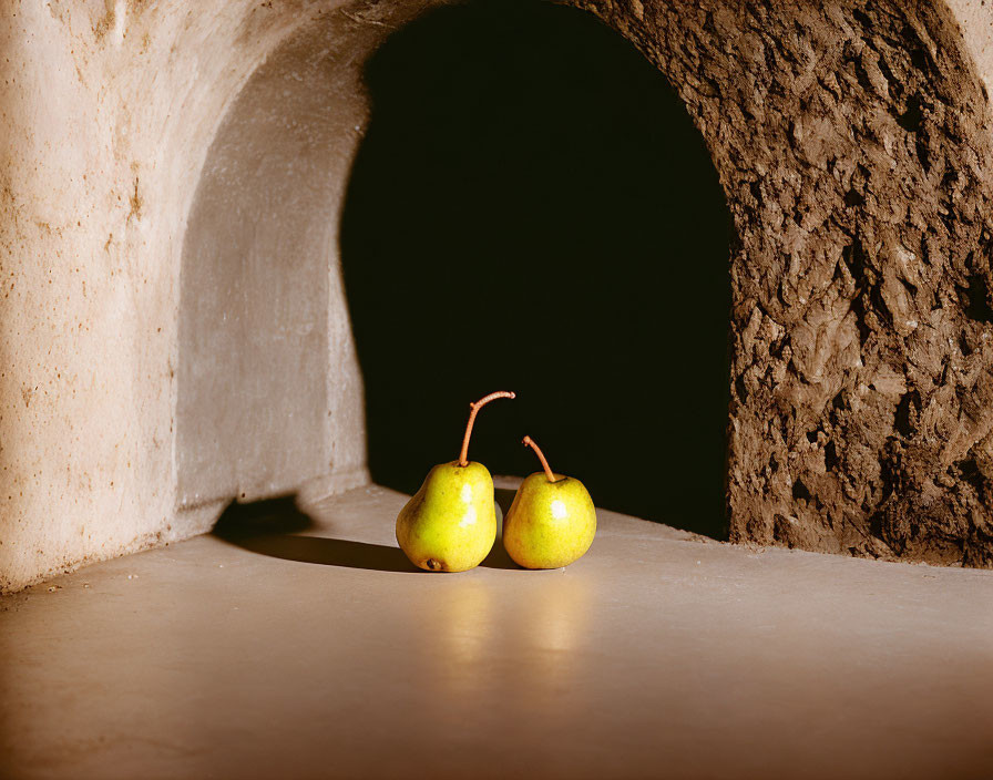 Ripe pears with stems on flat surface beside tunnel-like structure