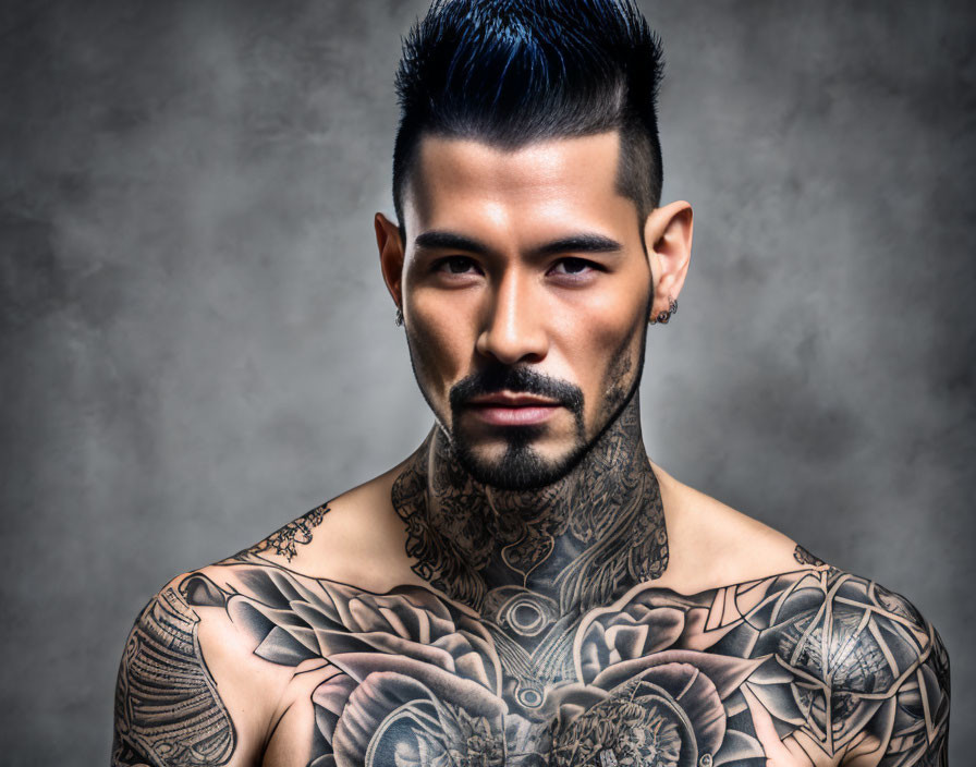 Man with Mohawk and Chest Tattoos Poses on Grey Background