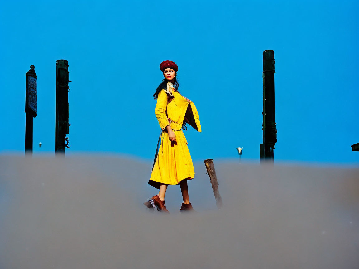 Woman in Yellow Coat and Red Beret in Urban Setting Against Blue Sky