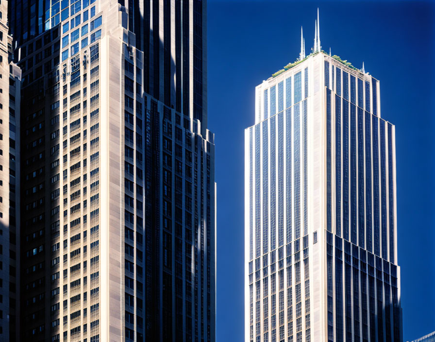 Twin skyscrapers against blue sky with sunlight reflection