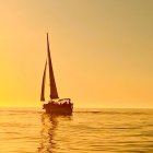 Tranquil seascape with sailboat on calm waters under golden sky