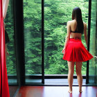 Person in Red Skirt Standing by Window with Green Foliage View