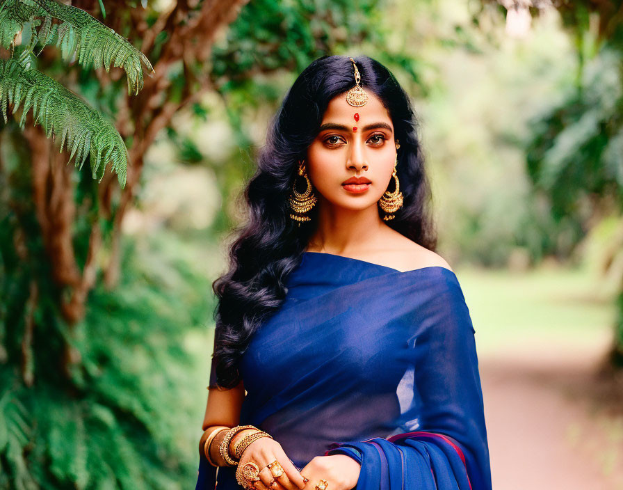 Traditional Indian Attire Woman Poses in Greenery with Gold Jewelry